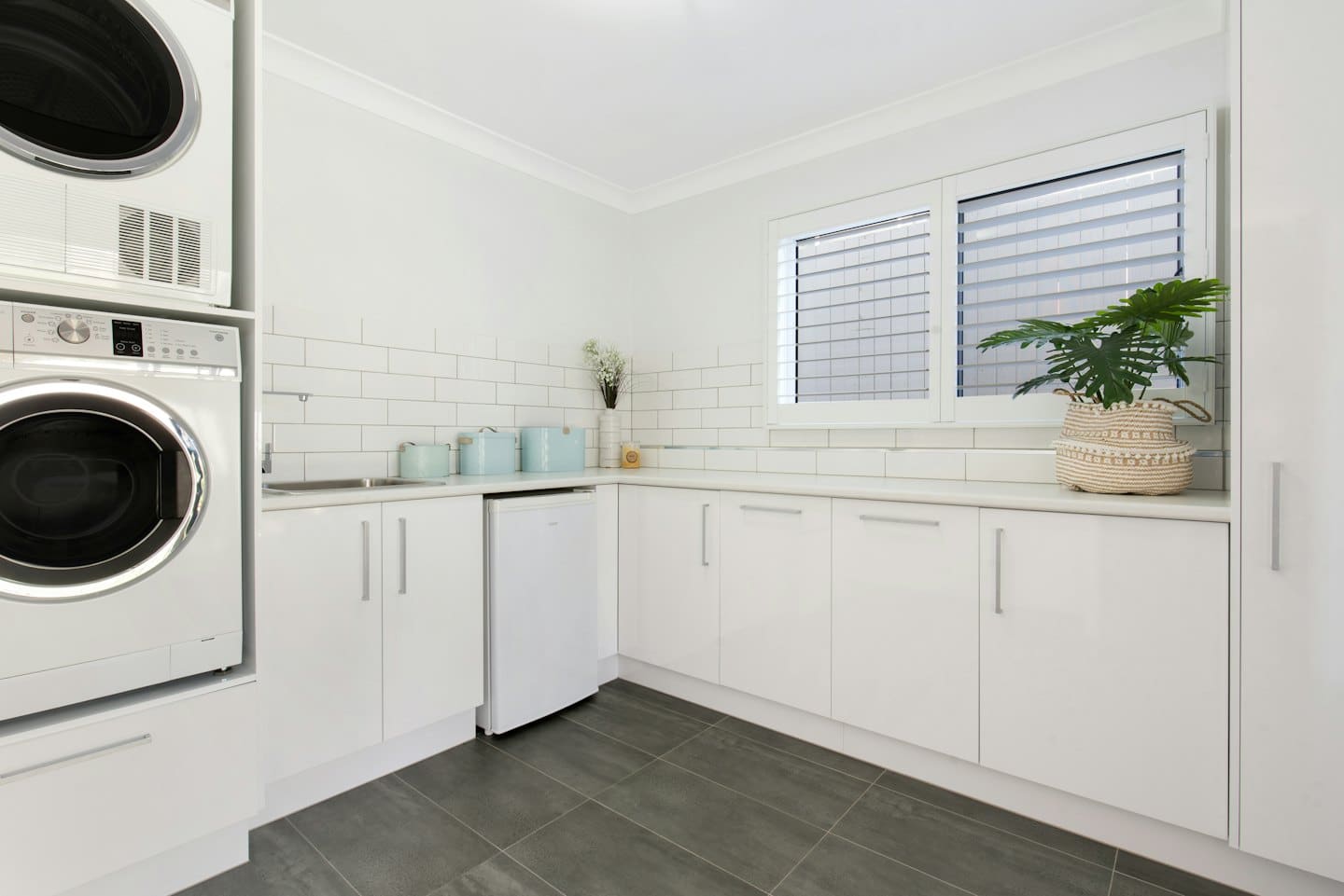 Modern laundry room with stacked white washer and dryer.
