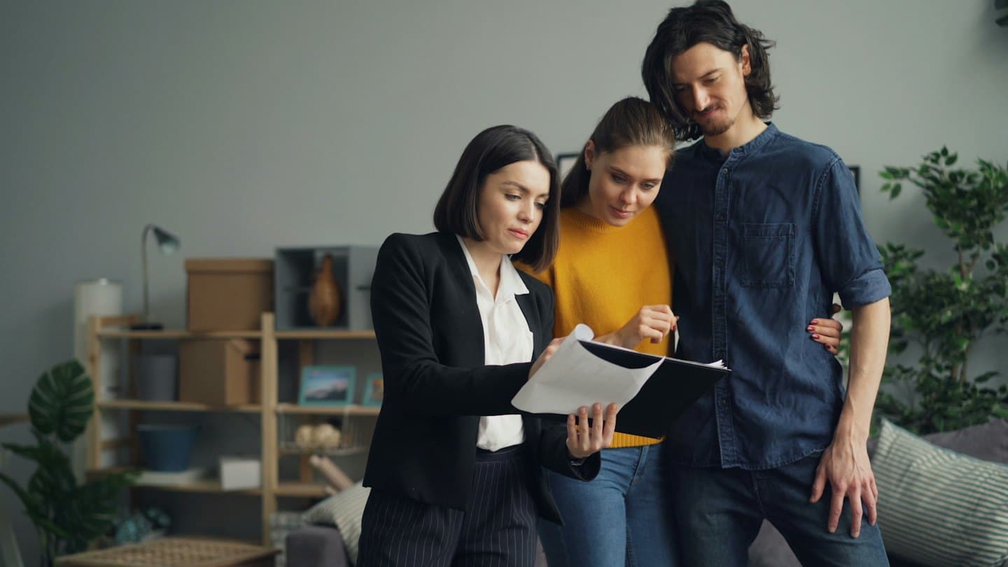 Real estate agent shows documents to a couple in a modern home.