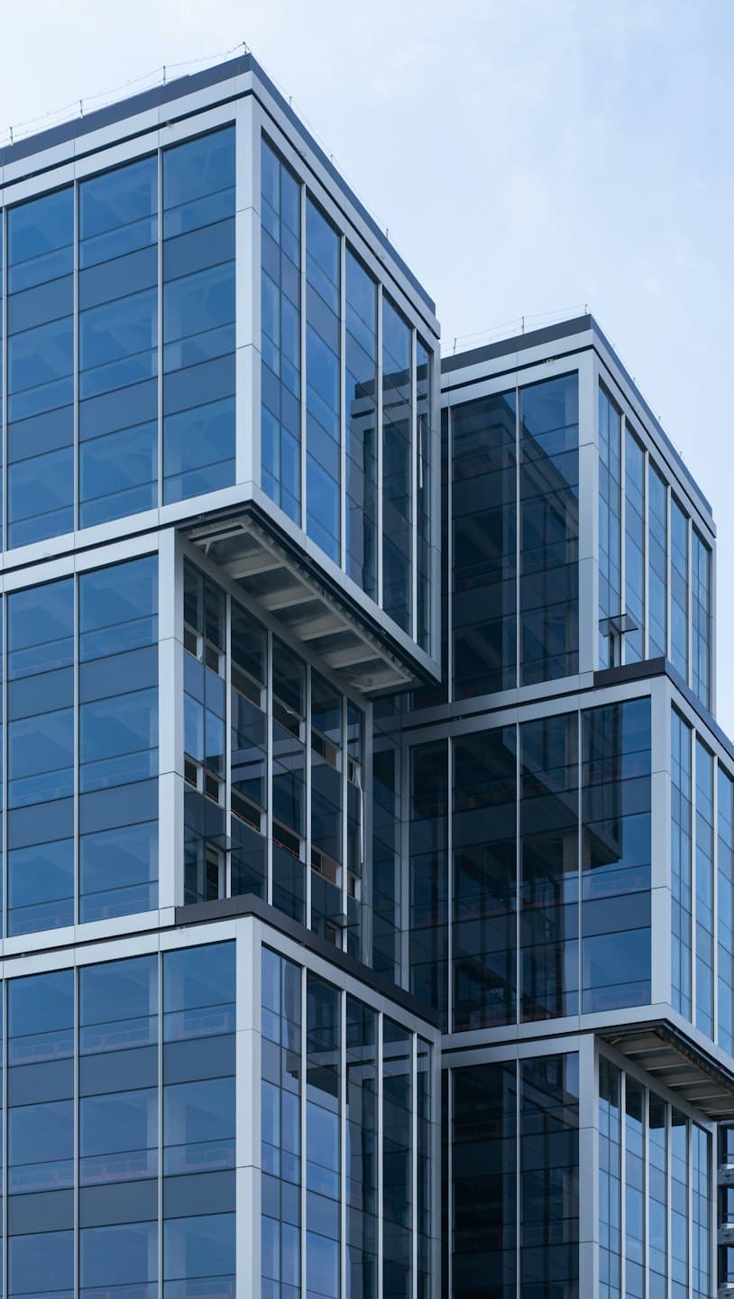 Modern glass and steel building with cantilevered geometric blocks.